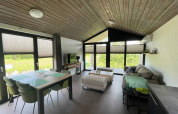 Salón moderno de planta abierta en la cabaña De Parel, Vakantiepark de Zeeuwse Parel, Países Bajos, con ventanales grandes.