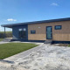 Moderne lodge ved navn Dijkzicht med træfacade og store vinduer under en blå himmel, set udefra.