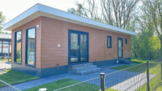 Moderno lodge Parkzicht al Vakantiepark de Zeeuwse Parel nei Paesi Bassi, circondato da alberi verdi.