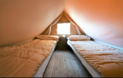 Twee eenpersoonsbedden in Airstay, een tiny house bij Papillon Country Resort, warme sfeer binnen.