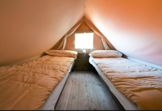 Two single beds inside Airstay, a tiny house at Papillon Country Resort in the Netherlands, wood flooring.