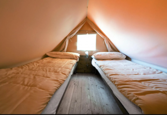 Twee eenpersoonsbedden in Airstay, een tiny house bij Papillon Country Resort, warme sfeer binnen.