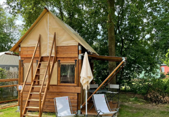 Airstay tiny house bij Papillon Country Resort in Nederland, met houten gevel en tuinstoelen buiten.