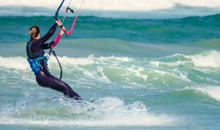 Personne en kitesurf en mer près de Vignole Mare SS, Sardaigne, Italie, portant combinaison et gilet.