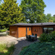 Billede af Heide lodge ved Bungalowpark Het Verscholen Dorp i Holland omgivet af frodigt grønt.