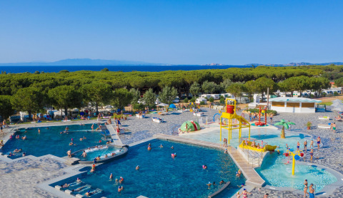 Overview of pools and splash park at Camping Village Baia Blu La Tortuga, surrounded by trees and near the sea.