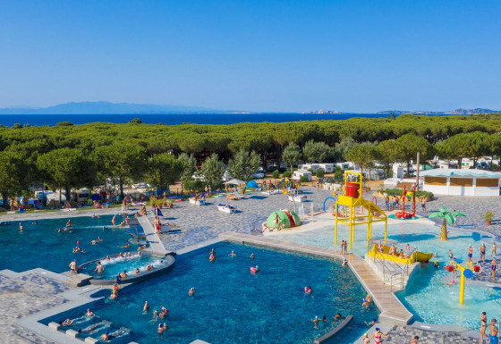 Panoramica delle piscine del Camping Village Baia Blu La Tortuga in Sardegna, circondate da alberi e mare.