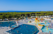 Panoramica delle piscine del Camping Village Baia Blu La Tortuga in Sardegna, circondate da alberi e mare.