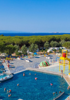Vista general de las piscinas en Camping Village Baia Blu La Tortuga, cerca del mar y rodeado de árboles.