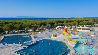 Vista general de las piscinas en Camping Village Baia Blu La Tortuga, cerca del mar y rodeado de árboles.