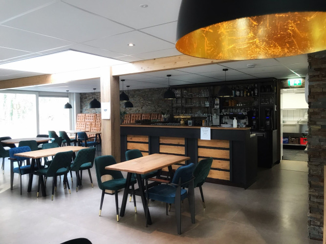 Moderne café- en barruimte met houten tafels en gestoffeerde stoelen in Bospark De Brenkberg, Limburg, Nederland.