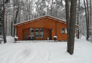 Holzhütte im verschneiten Wald im Bospark De Brenkberg, einem Ferienpark in Limburg, Niederlande.