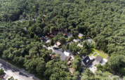Luftfoto af Bospark De Brenkberg feriepark, omgivet af tæt skov i Limburg, Holland, med huse og veje.