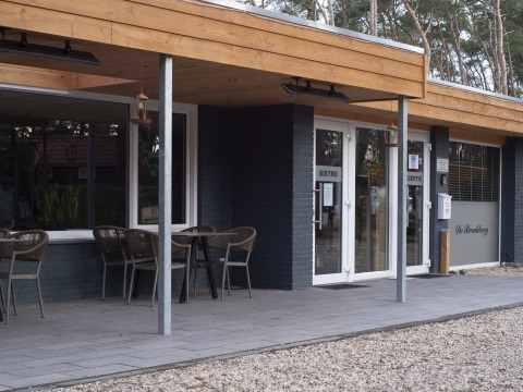 Eingang zum Ferienpark Bospark De Brenkberg in Limburg, Niederlande, mit Bistro und Außensitzplätzen.
