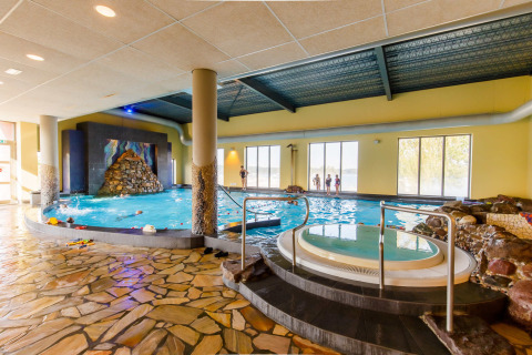 Piscina cubierta y jacuzzi en el Vakantiepark Leukermeer, un parque vacacional en Limburgo, Países Bajos, con ventanas grandes.