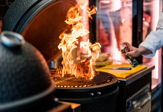Ein Koch grillt Fleisch über offenem Feuer am Vakantiepark Leukermeer in Limburg, Niederlande.