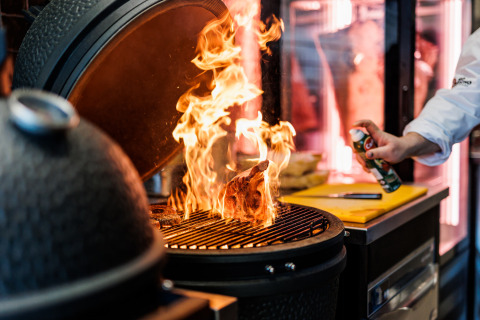 Een chef grilt vlees boven open vuur op een barbecue bij Vakantiepark Leukermeer, Limburg, Nederland.