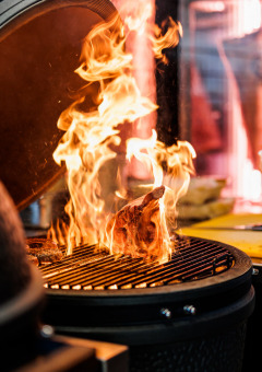 Een chef grilt vlees boven open vuur op een barbecue bij Vakantiepark Leukermeer, Limburg, Nederland.