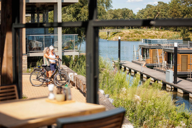 Deux personnes avec des vélos profitent de la vue sur l’eau à Vakantiepark Leukermeer, Limburg, Pays-Bas.