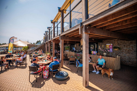 Zona de terraza al aire libre en Vakantiepark Leukermeer con personas y un perro disfrutando en Limburg, Países Bajos.