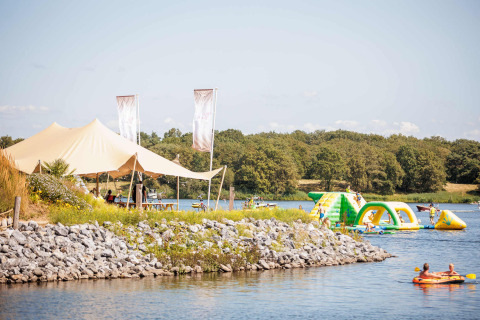 Día veraniego en Vakantiepark Leukermeer, Limburg, Países Bajos, con parque acuático inflable y carpa en la orilla.