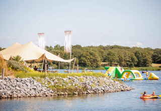 Scène estivale au Vakantiepark Leukermeer, Limbourg, Pays-Bas, avec parc aquatique et tente au bord du lac.