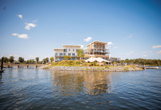 Modern holiday house on a small lake island at Vakantiepark Leukermeer, Limburg, Netherlands, under clear sky.