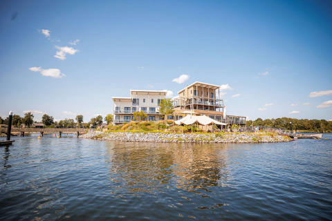 Modern holiday house on a small lake island at Vakantiepark Leukermeer, Limburg, Netherlands, under clear sky.