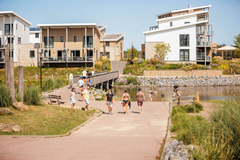 Vakantiepark Leukermeer holiday park in Limburg, Netherlands, with modern houses, water, and people walking.