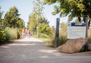 Famiglia passeggia su un sentiero alberato nel Vakantiepark Leukermeer, parco vacanze in Limburgo, Paesi Bassi.