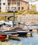 Boten aangemeerd bij een jachthaven nabij moderne appartementen en wandelaars in Well, Limburg, Nederland.