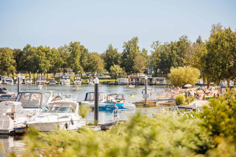 Boats docked and people enjoying the beach at Vakantiepark Leukermeer holiday park in Limburg, Netherlands.