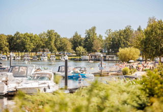 Barche ormeggiate e persone in spiaggia a Vakantiepark Leukermeer, parco vacanze in Limburg, Paesi Bassi.