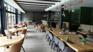 Restaurante moderno y luminoso con mesas de madera en un parque vacacional con alojamiento glamping.