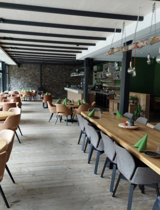 Licht, modern restaurant met houten tafels en grote ramen op een vakantiepark met glampingaccommodaties.