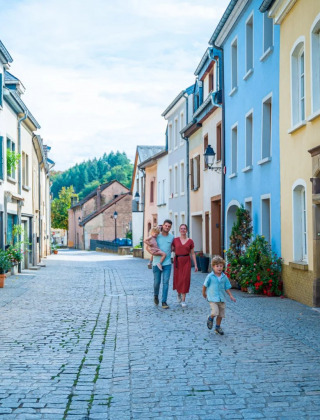 Familia paseando por una calle empedrada rodeada de casas coloridas en un tranquilo parque con glamping.