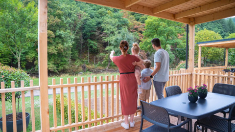 Une famille admire la vue depuis son hébergement glamping dans un parc de vacances entouré de verdure.