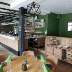 Zona de bar y restaurante moderna con paredes verdes y muebles de madera en un parque de vacaciones glamping.