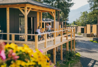 Huéspedes disfrutan de una comida en la terraza de una cabaña glamping en un parque vacacional entre la naturaleza.