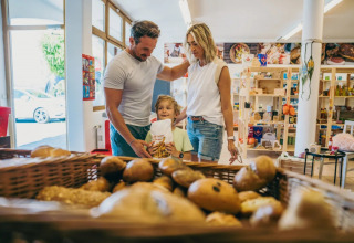 Familie kauft Brot in einer kleinen Bäckerei eines Ferienparks mit Glamping-Unterkünften.