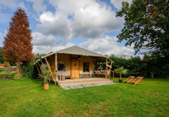 Safari-telt Cottage Kaa ved Camping Vossenberg i Holland med terrasse, havemøbler og grøn have.
