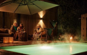 Tres personas disfrutan junto a la piscina y sauna por la noche en Unbrick One | Sauna and Pool en Brinckerduyn, Países Bajos.