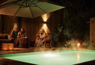 Tres personas disfrutan junto a la piscina y sauna por la noche en Unbrick One | Sauna and Pool en Brinckerduyn, Países Bajos.
