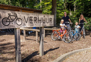 Familie mietet Fahrräder am Verleihschild im Ferienpark De Thijmse Berg, Utrecht, Niederlande.