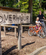 Familia alquila bicicletas junto a un cartel de alquiler en De Thijmse Berg, Utrecht, Países Bajos.