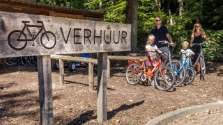 Familia alquila bicicletas junto a un cartel de alquiler en De Thijmse Berg, Utrecht, Países Bajos.