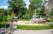 Legeplads i De Thijmse Berg feriepark i Utrecht, Holland, med rutsjebaner og et legetræskib i sandet.