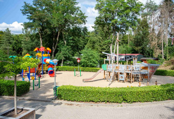 Spielplatz im Ferienpark De Thijmse Berg, Utrecht, Niederlande, mit Rutschen und Piratenschiff im Sand.