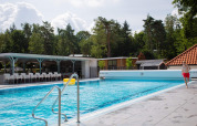 Udendørs swimmingpool i De Thijmse Berg ferieland i Utrecht, Holland, med træer og bygninger omkring.