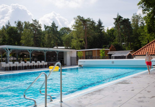 Außenpool im Ferienpark De Thijmse Berg in Utrecht, Niederlande, umgeben von Bäumen und Gebäuden.